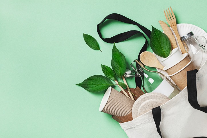 Plastic free set with eco cotton bag, glass jar, green leaves and recycled tableware top view. Zero waste, eco friendly concept. Flat lay.