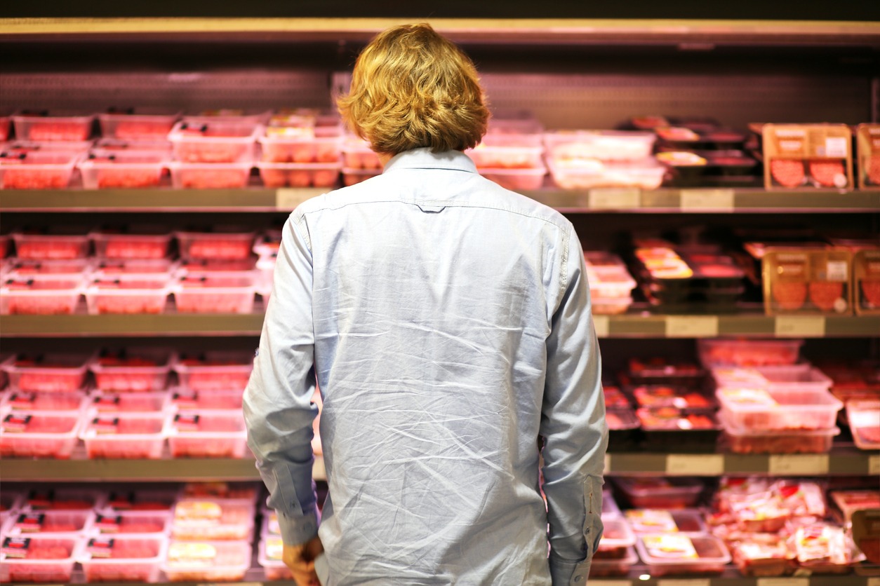 a young man choosing meat from the grocery store