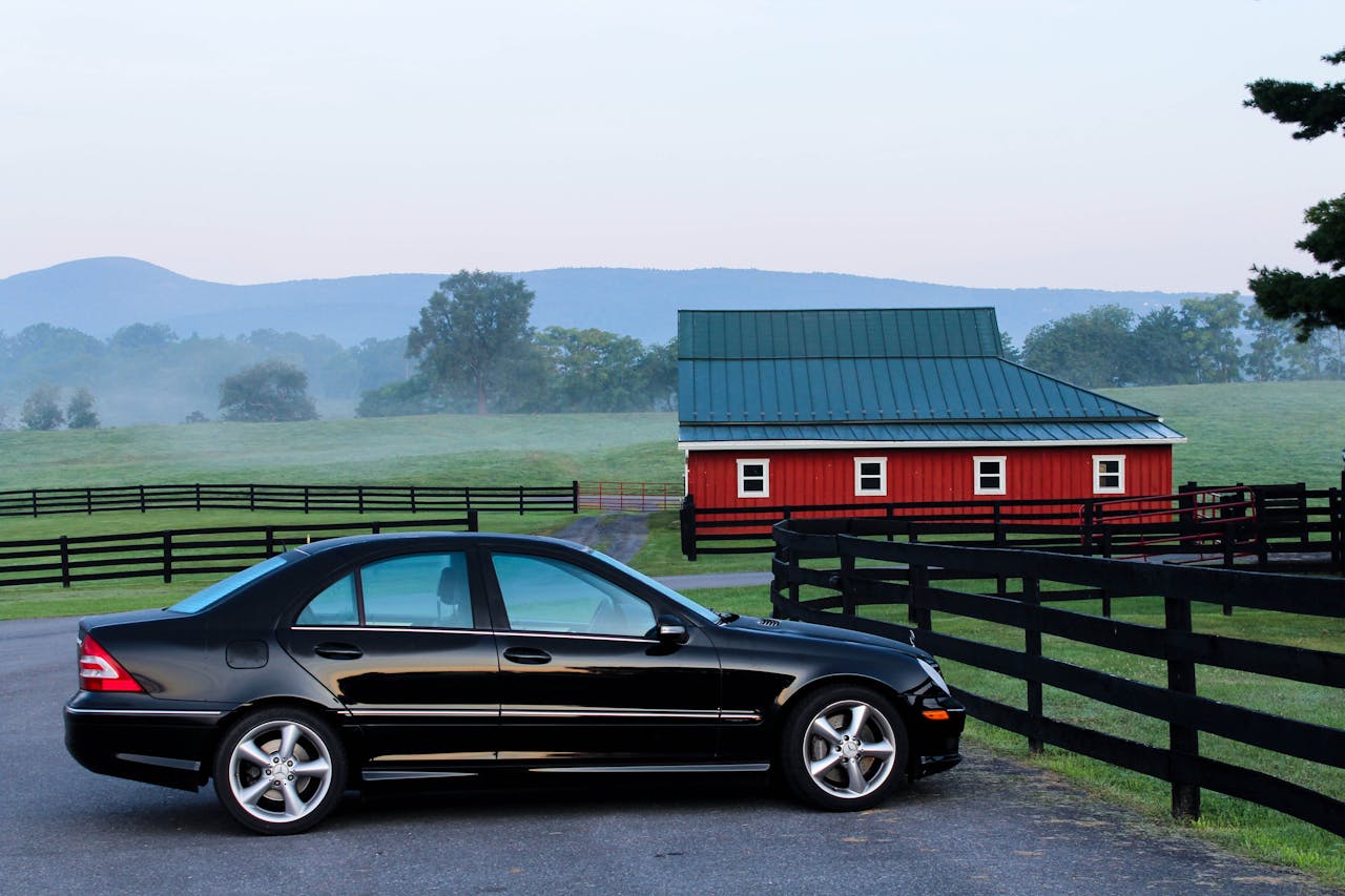 a car parked on a ranch with a red barn