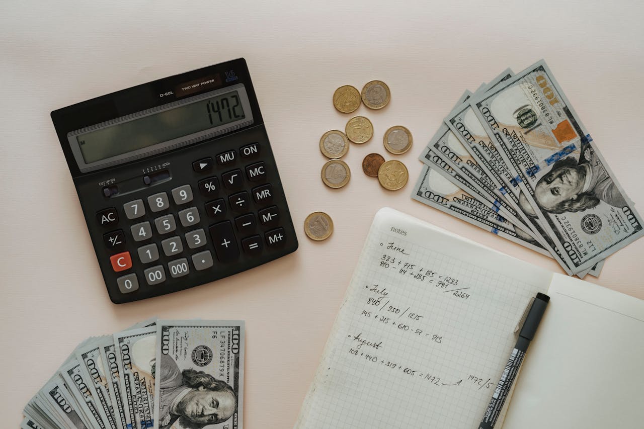 calculator, notebook, and bills on a table
