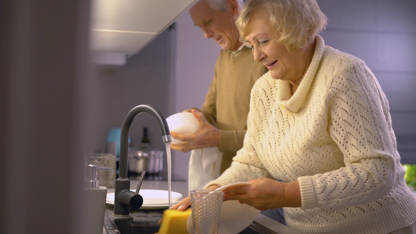 senior couple washing the dishes at night