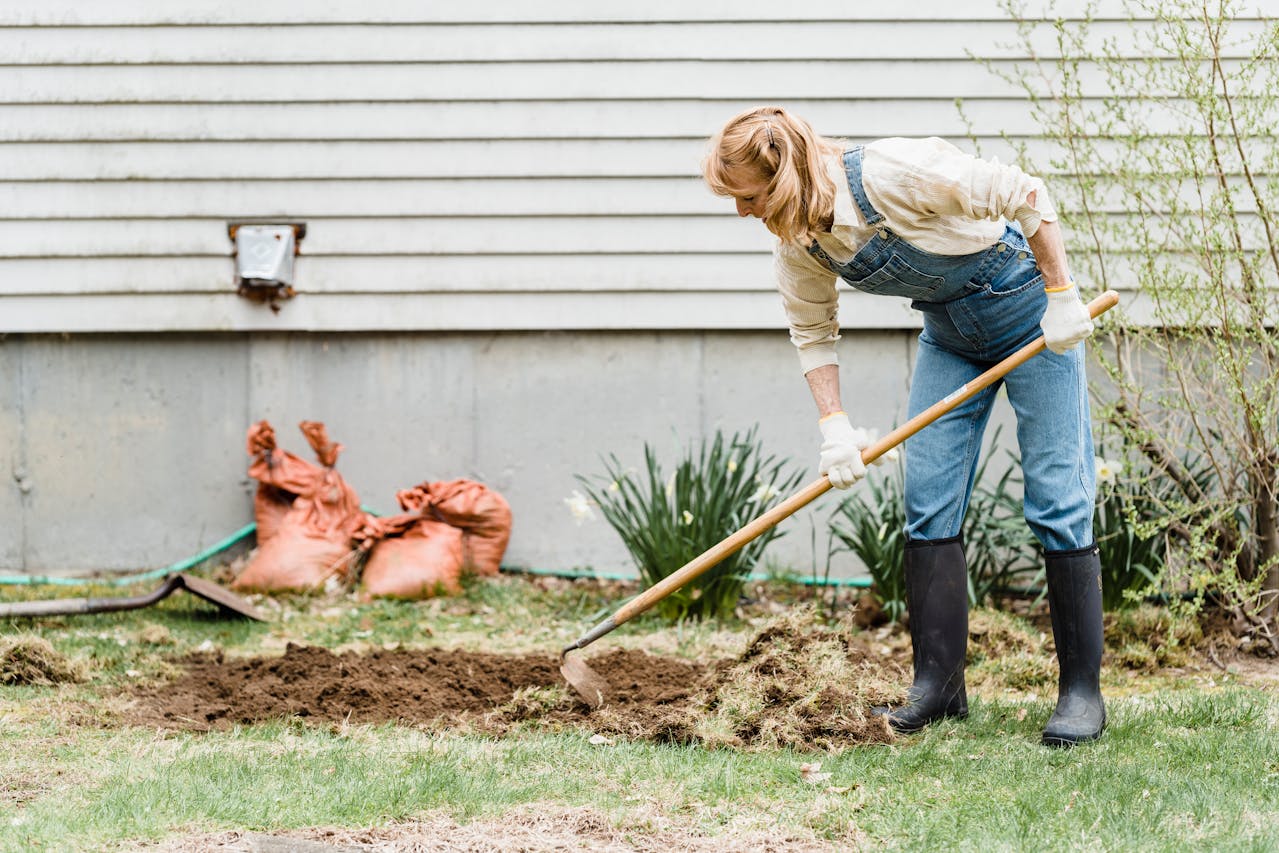 a woman using a gardening tool to till the soil
