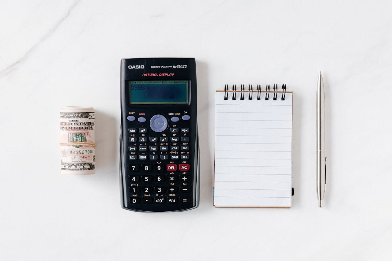 a wad of cash, a calculator, a notebook and pen
