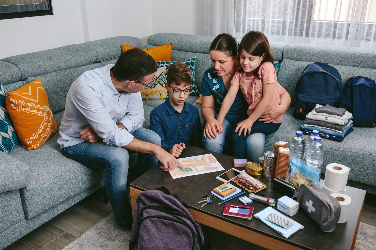 father explaining to his family the assembly point map while preparing emergency backpacks