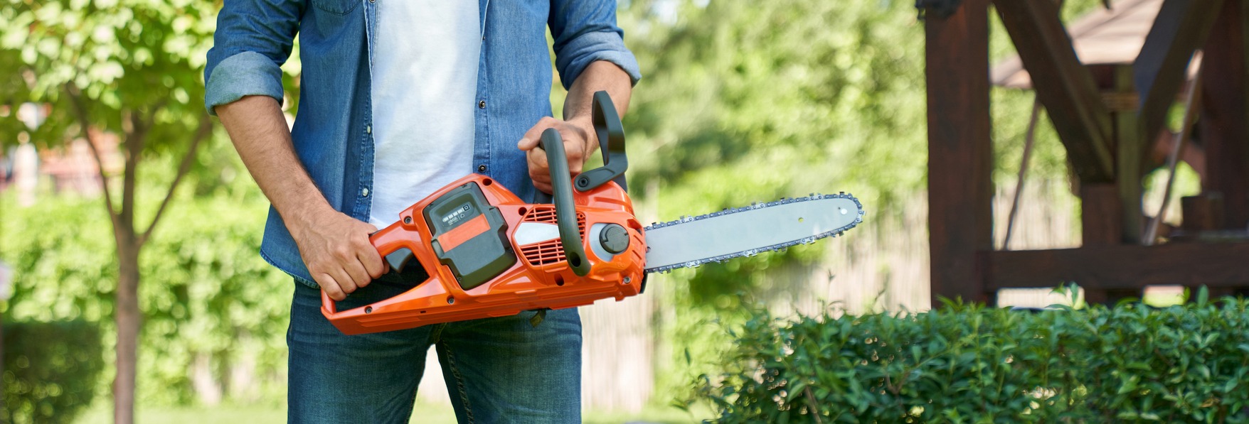 Unrecognizable craftsman standing with cordless electric chain saw