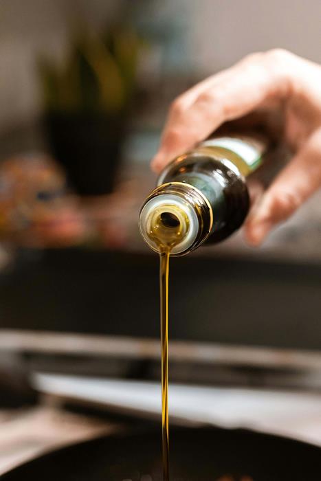 A person pouring olive oil