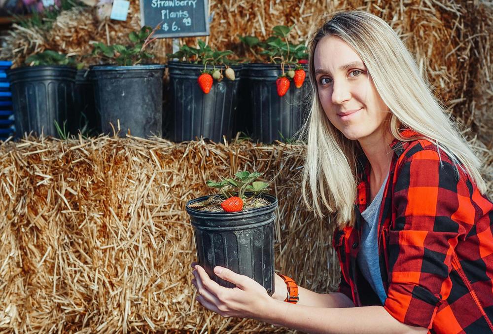 A woman holding a pot with strawberry plant