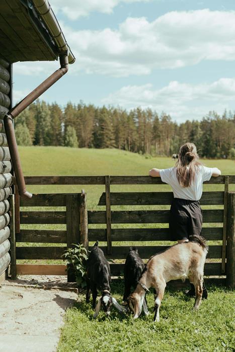 Woman standing beside brown wooden fence