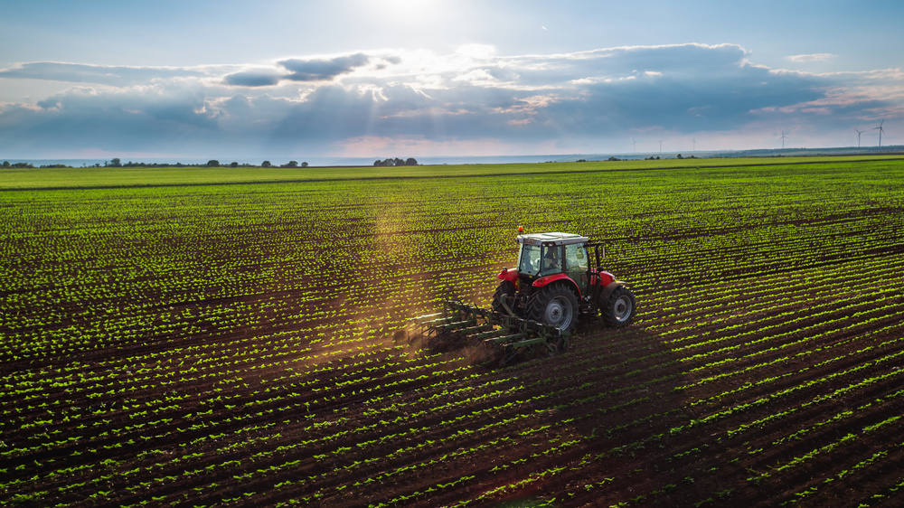 Tractor cultivating field at spring, aerial view