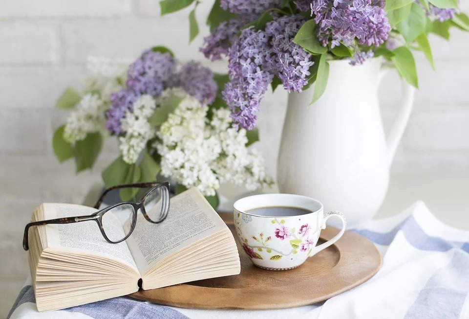 Image of home flowers with a cup of coffee and a book for relaxing.