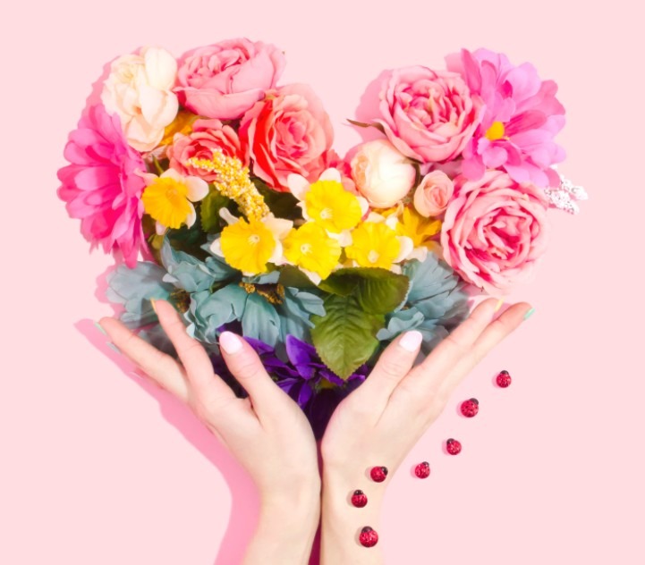 Hands holding up flowers in the shape of a heart