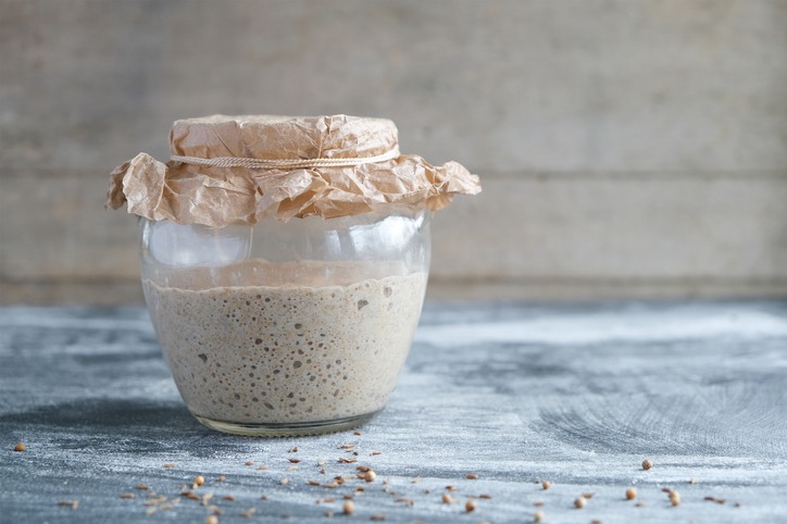 Rye sourdough on whole grain flour in glass jar on table, yeast-free leaven starter