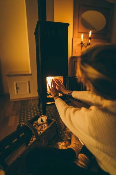 A woman warming her hands from chimney-fireplace